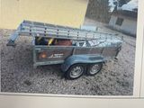 une photo d'un homme debout à côté d'un camion attelé à une remorque
