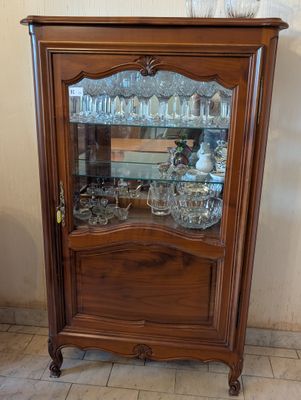 a wooden cabinet with a glass door and a vase on top of it