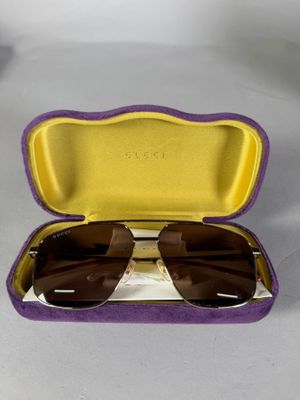 étui violet et jaune contenant des lunettes de soleil, posé sur une surface blanche