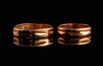 deux alliances en or sur une surface noire avec des reflets