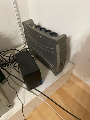 a computer that is sitting on a shelf in the corner of a room