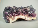 crystal cluster with purple crystals on a white surface
