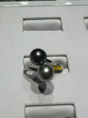 une bague ornée de deux perles noires, exposée dans une vitrine