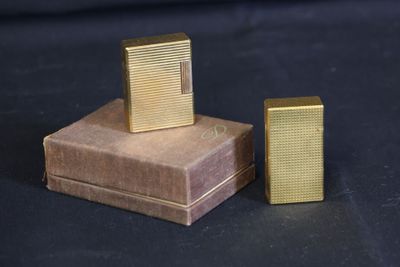 two gold lighters sitting on top of a box on a black surface