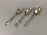 three silver spoons sitting on top of a table next to each other