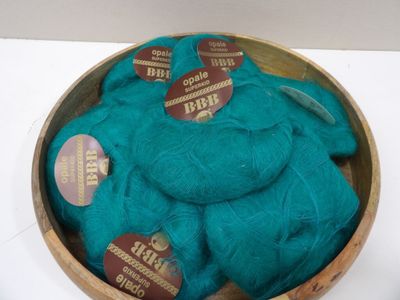 a wooden bowl filled with blue yarn on a white table