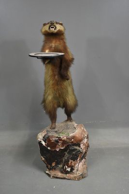 une statue représentant un écureuil tenant une assiette sur un rocher