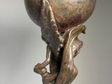 bronze sculpture of a woman holding a globe on her head