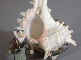 a figurine of a woman standing next to a shell