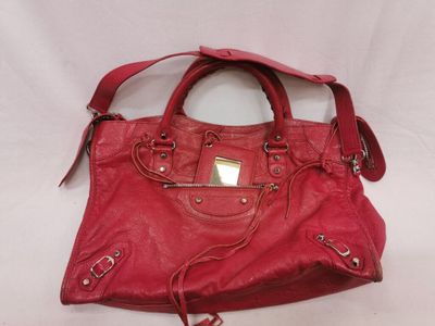 un sac à main rouge muni d'une étiquette, posé sur une surface blanche