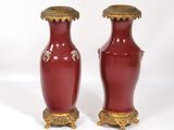 paire de vases rouges avec des bordures et des anses dorées sur fond blanc