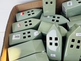 a cardboard box full of small green houses in it