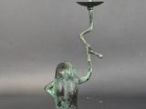 a bronze statue of a man holding a candelabra