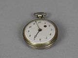 a silver pocket watch with a white face on a gray surface