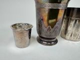 a silver cup next to a silver vase on a table