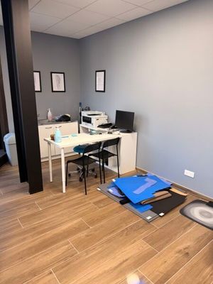une pièce avec un bureau, une chaise, une imprimante et d'autres objets posés par terre