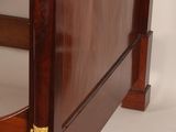 a bed that has a wooden frame with gold decorations on the headboard