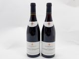 deux bouteilles de vin rouge posées l'une à côté de l'autre sur une surface blanche