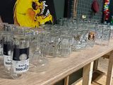 de nombreux verres vides posés sur une table, avec un tableau accroché au mur derrière eux