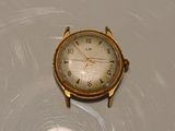 a gold watch sitting on a table with a white background