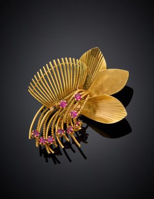 an image of a gold brooch with pink stones on a black background