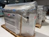 several pallets of mattresses wrapped in plastic sit on pallets in a warehouse