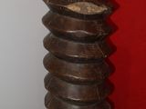 a tall wooden vase with a red wall in the background