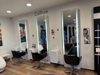 une photo d'un salon de coiffure avec des fauteuils et des miroirs