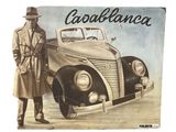 a man standing next to an old car with a hat on