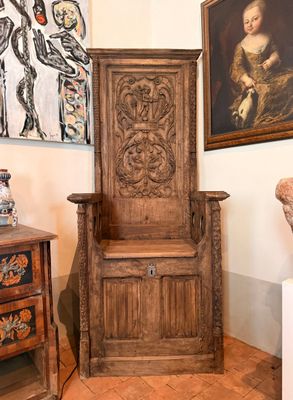 une chaise en bois dans une pièce où est accroché un tableau au mur
