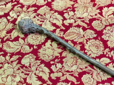 un bâton d'argent posé sur une nappe rouge et dorée