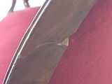 a close up of a red chair with a broken arm