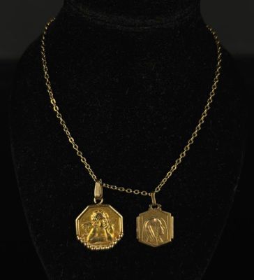 a gold necklace with two small medallions on a black mannequin