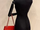 a mannequin holding a red purse on a stand