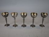 four silver goblets are lined up on a table