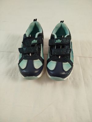 pair of toddler ' s shoes on a bed with a white sheet