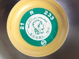 a yellow frisbee in a metal bowl with a green label