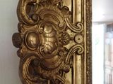 a gold mirror with a face on it in the corner of a room