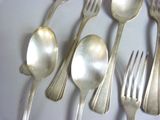 five silver spoons and two silver spoons on a white plate