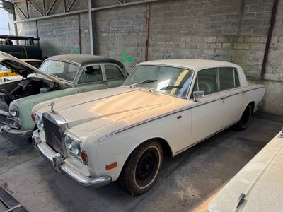 two old cars parked in a garage next to each other