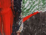 a close up of a red and black vase with a green leaf on it