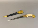 pair of gold and black handled knives on a gray surface
