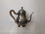 a silver tea pot sitting on a glass table