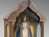 une image représentant un petit sanctuaire en bois abritant la statue d'une femme vêtue d'une robe bleue