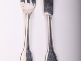 two forks and a knife on a white table