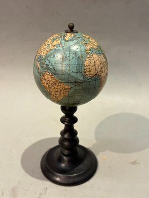 un petit globe bleu et vert posé sur un socle noir