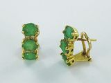 une paire de boucles d'oreilles en or et pierres vertes sur fond blanc