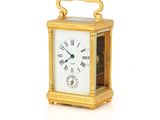 une petite horloge en or avec des chiffres romains