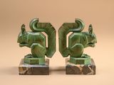 two green sculptures of animals on marble bases against a beige background