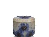the candle has a blue flower on it and is sitting on a white surface